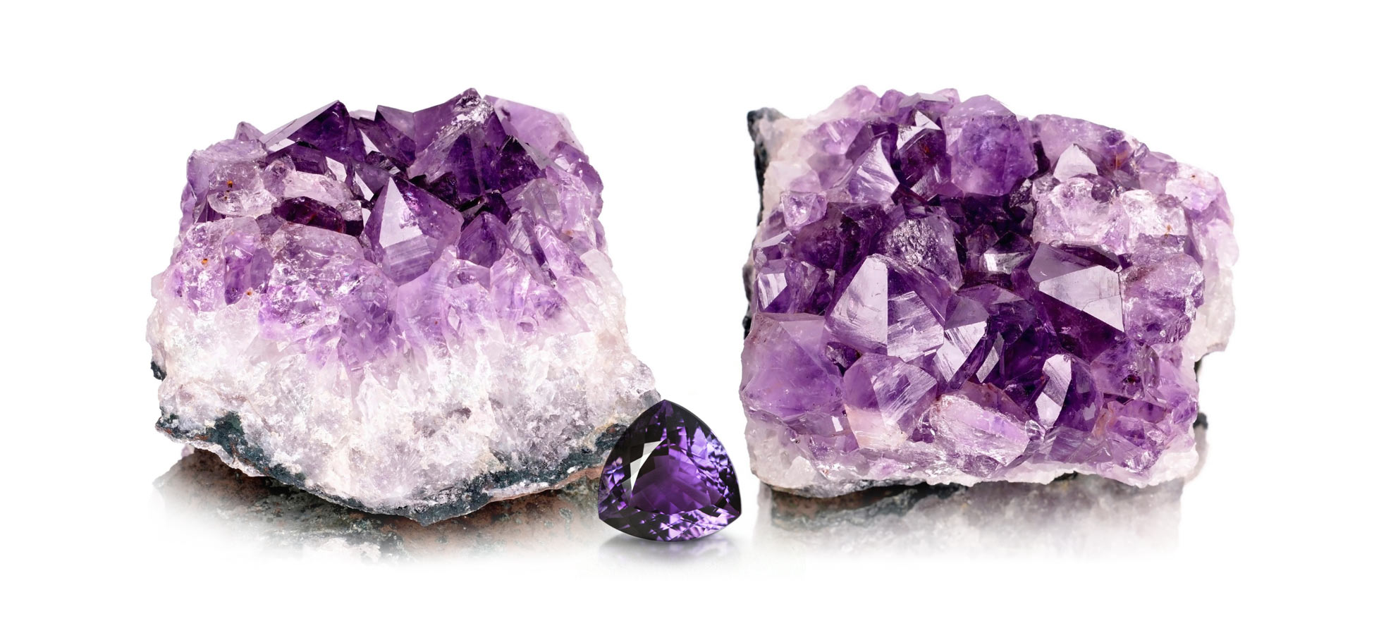 Some examples of raw amethyst quartz crystals alongside a faceted amethyst gemstone