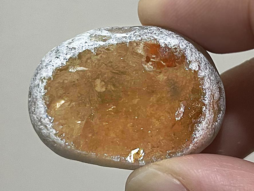 A tumbled citrine specimen with a sliced window area