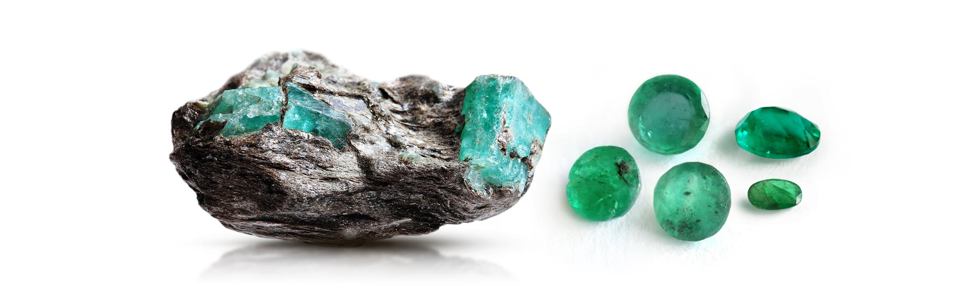 emerald specimen in host rock matrix as well as a few heavily included emerald gemstones