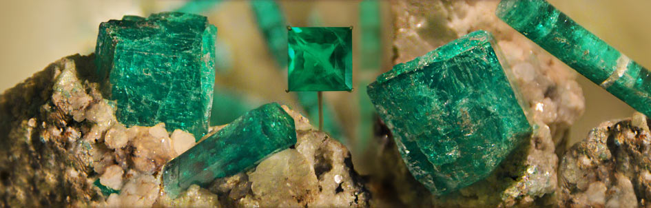 emerald gemstone on top of a group of rough crystal specimens